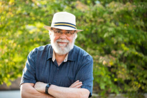 Steven Ruggles standing with arms crossed in front of trees