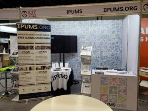 The IPUMS exhibit booth with IPUMS banners, counter, and TV.