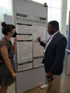 Maya standing by her research poster while speaking to a conference attendee