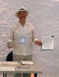 Dr. Bob McCaa standing behind a table with stacks of paper 